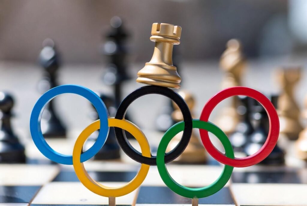 Alt text: Intense Olympic chess match with focused players strategizing amidst intricate chess pieces.